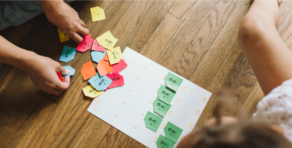 Two children joyfully playing with vibrant paper scattered on the floor, showcasing creativity and imagination.