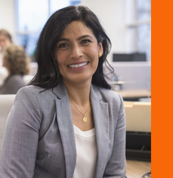 A professional woman in a business suit seated at a desk, focused on her work in a modern office environment.