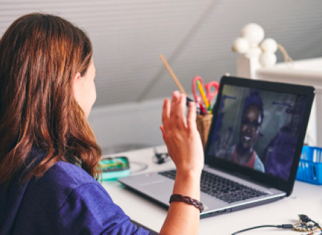 A girl seated at a desk, engaged in a video chat on her laptop, focused and attentive to the screen.