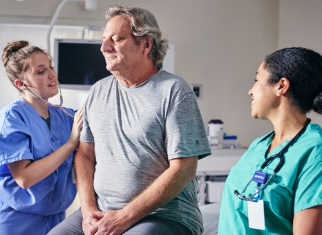 A nurse converses with a man in a hospital setting, providing care and support during his visit.