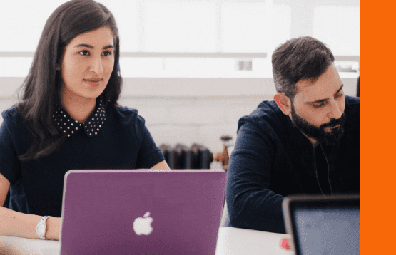 A diverse group of professionals collaborating on laptops in a modern office environment.